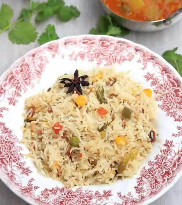 Vegetable pulao served in a big plate with a side in the background