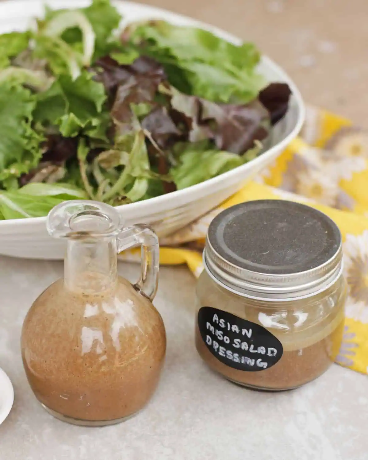 Asian Miso dressing in couple of jars with salad in the background.