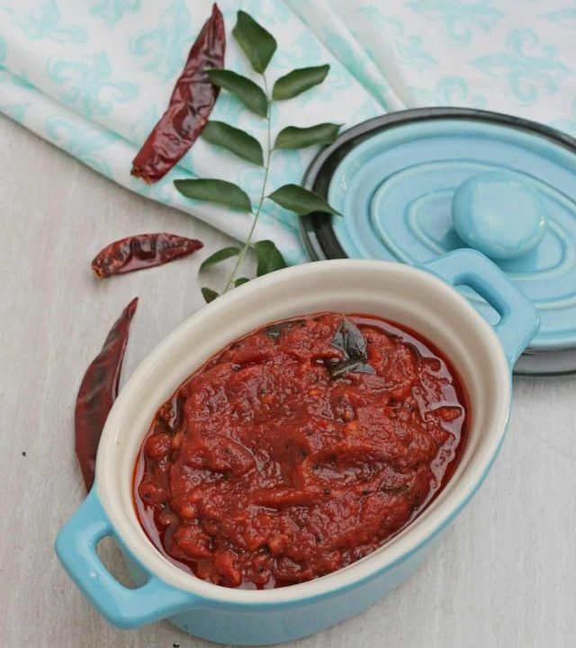 Kara chutney in a bowl with red chilies and curry leaves in side