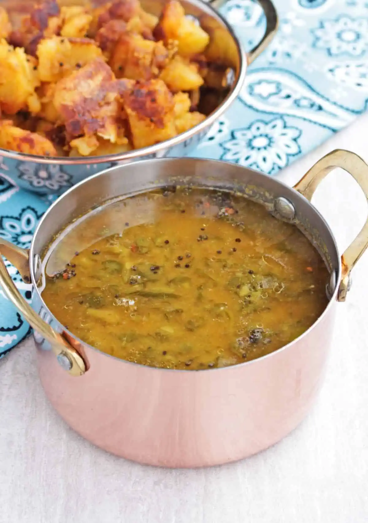 Sambar with fresh fenugreek leaves in a copper bowl.