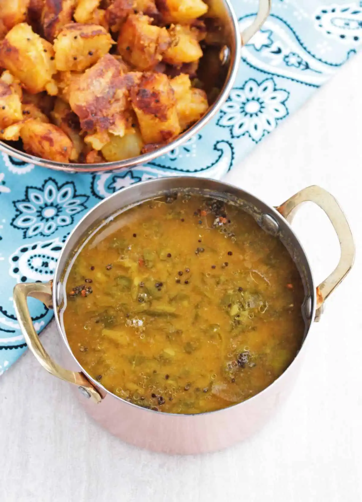 Sambar with potato curry in the background.