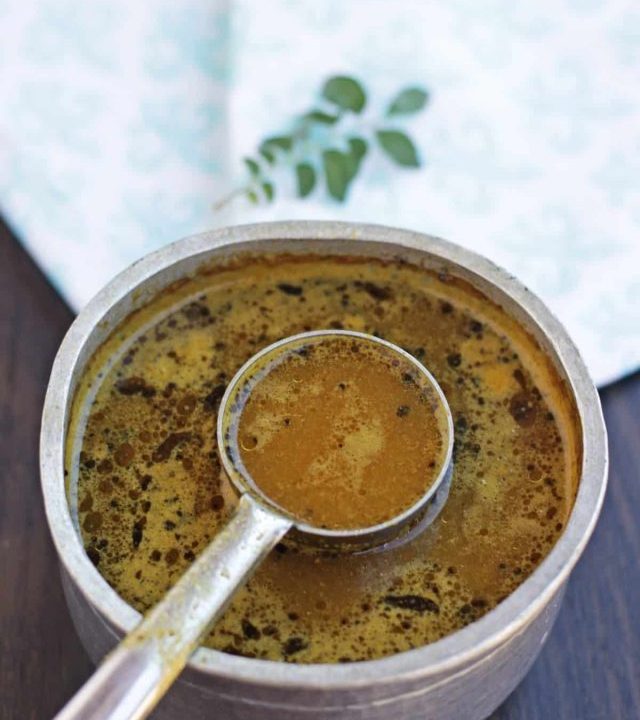 rasam in a vessel with ladle inserted