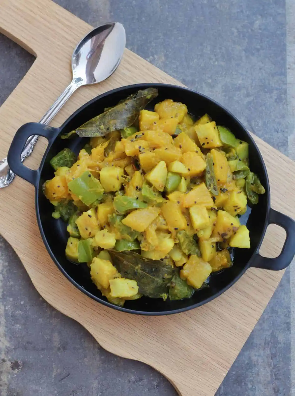 Curry with panch phoran spice in a black plate. 