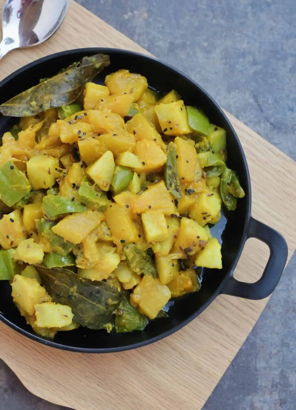 Mixed vegetable curry in a black plate.