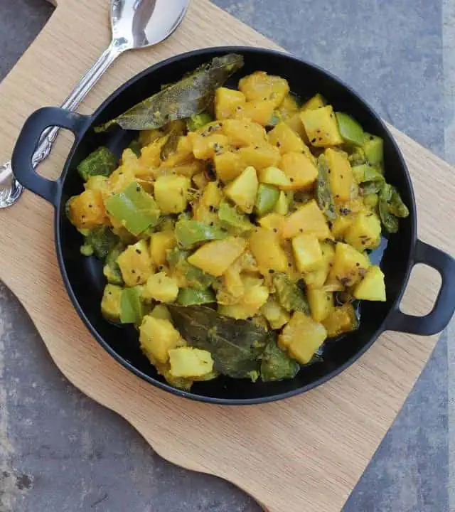 Curry with panch phoran spice in a black plate.