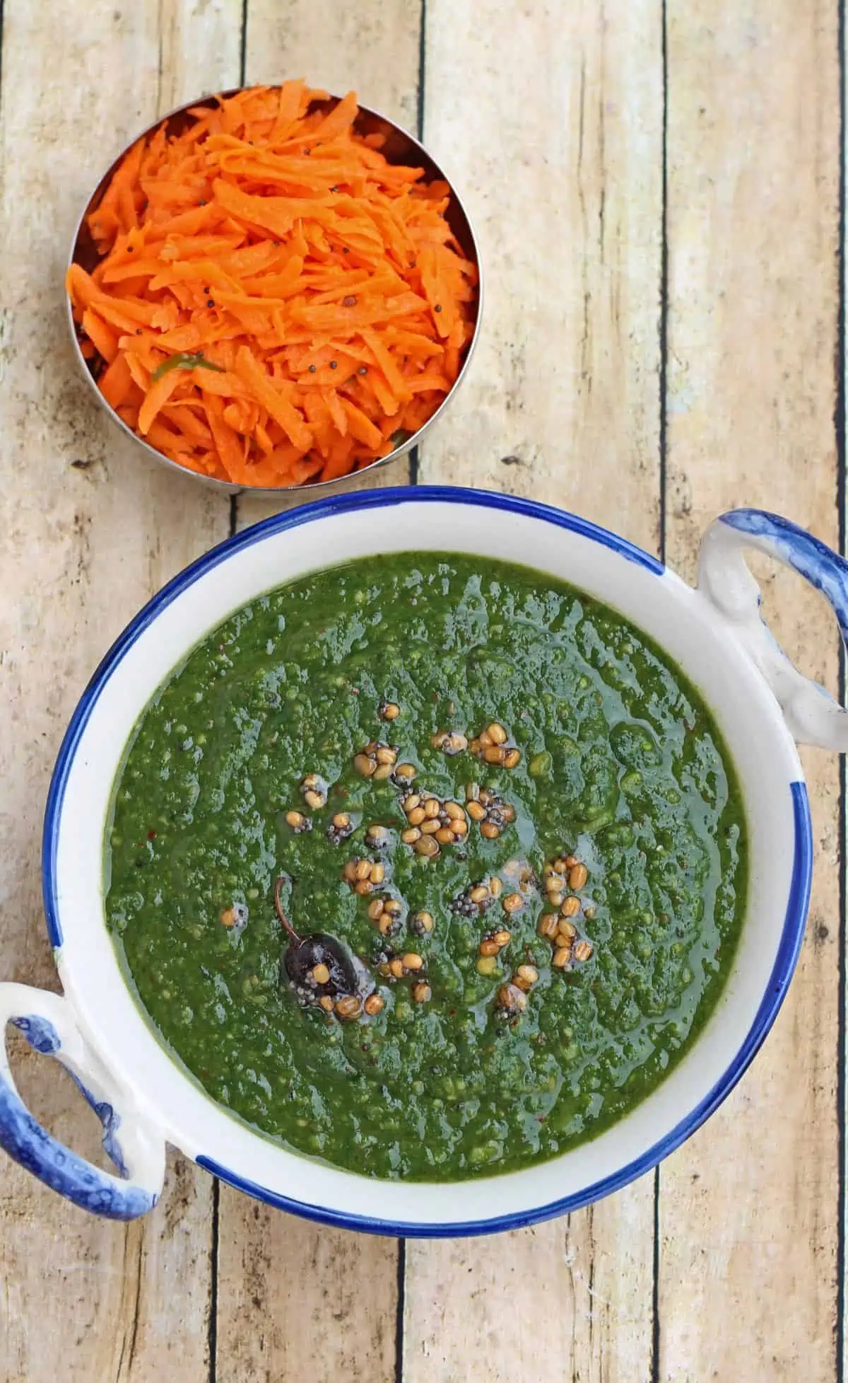 keerai kootu with seasoning on top in a white and blue bowl