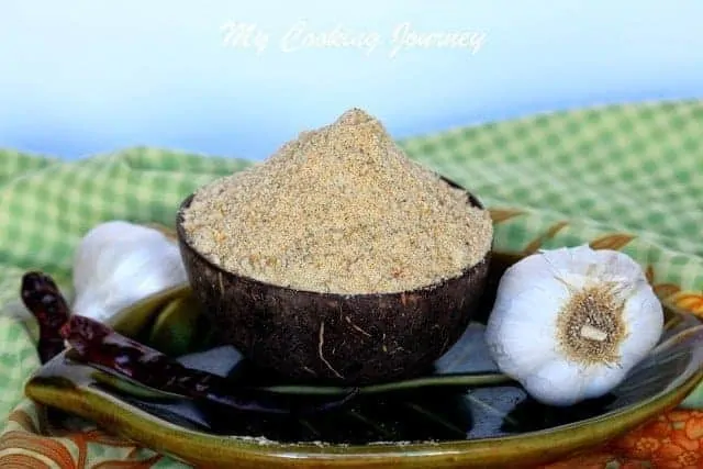 Poondu Paruppu Podi in a bowl with  garlic on side