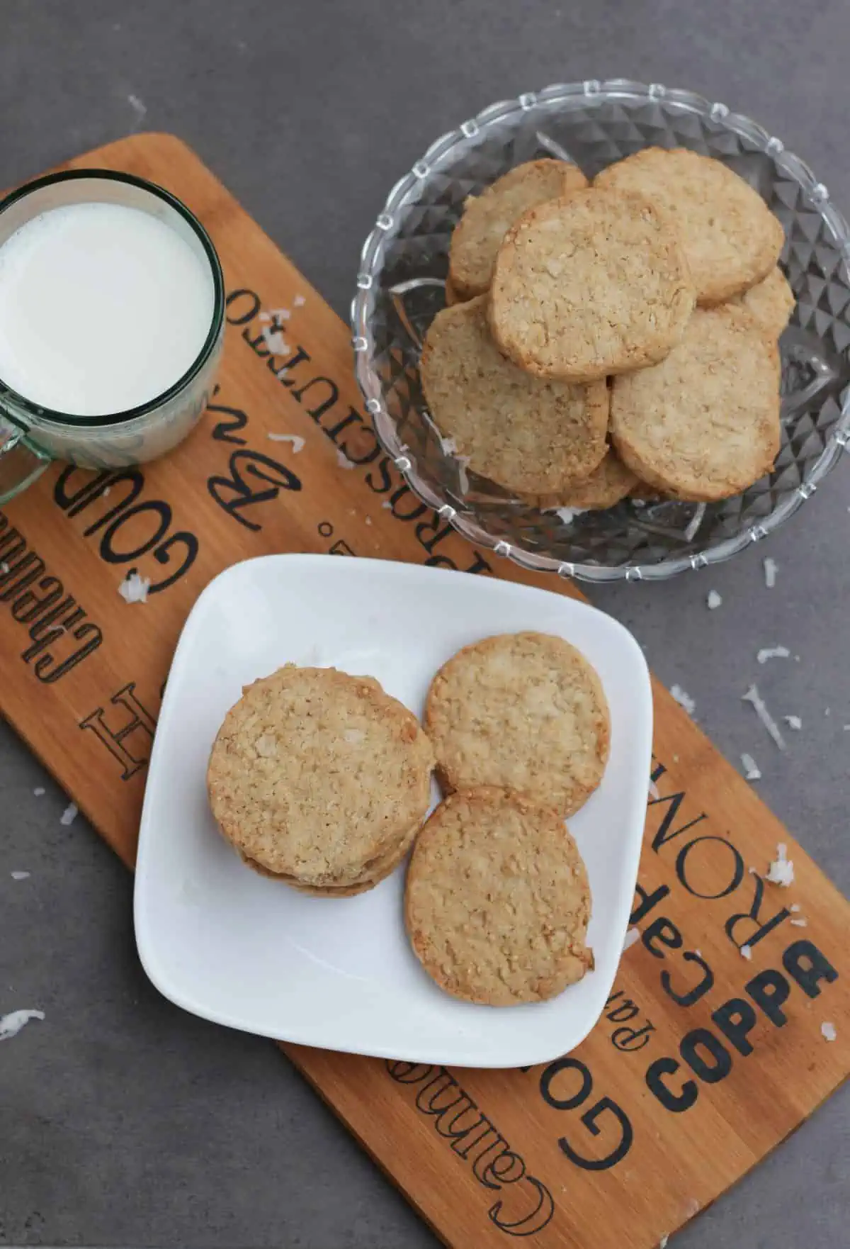 Top view of stacked cookies in a bowl and plate and milk in a mug.