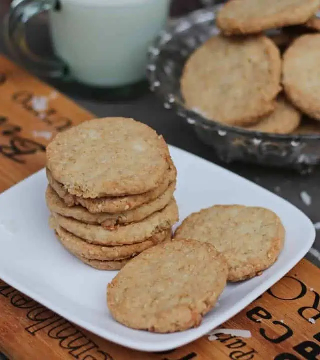 coconut and sesame cookies in a plate with milk in the back.