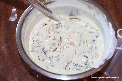 Adding yogurt to cooked eggplant spice mixture.