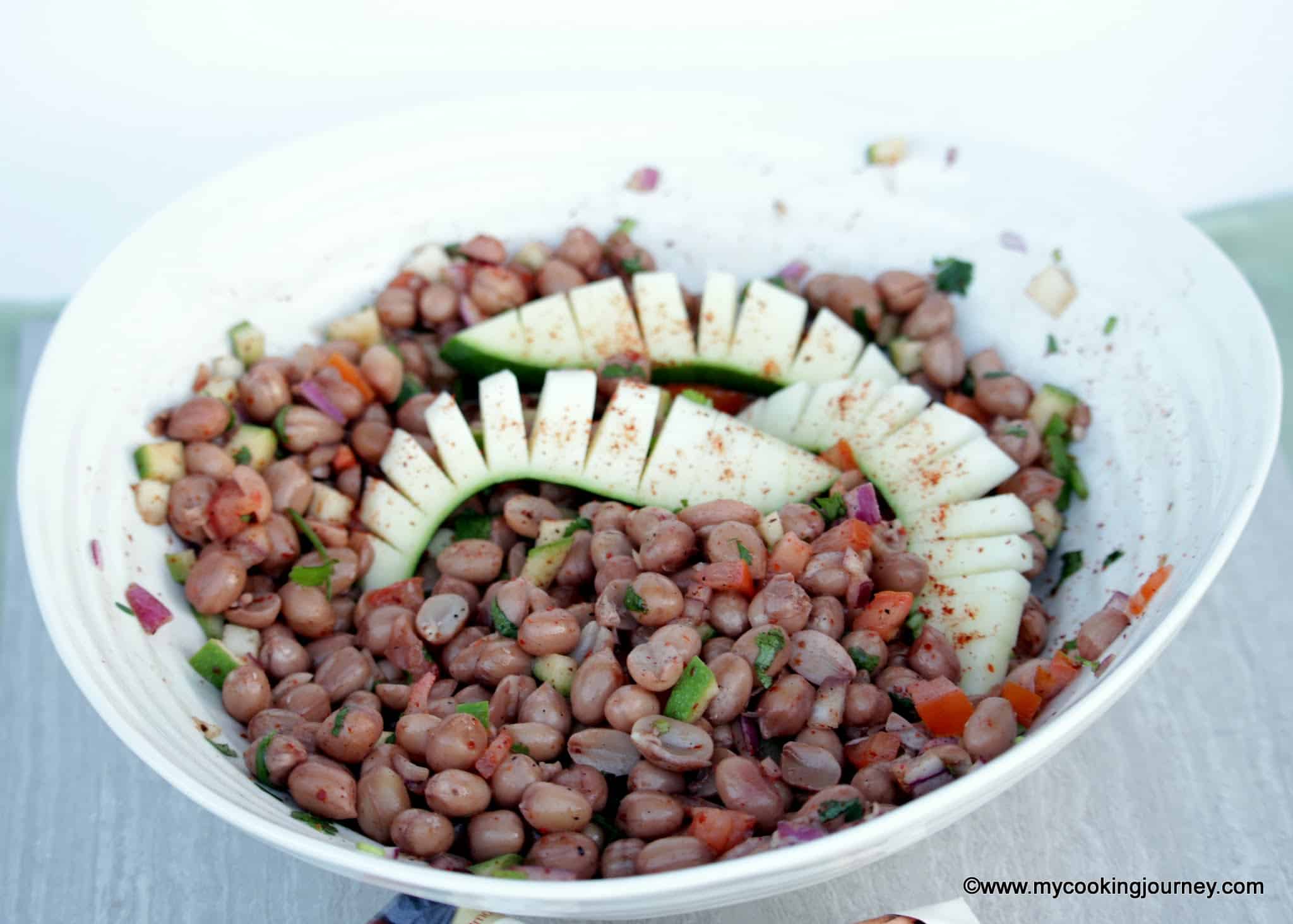 Spiced masala peanuts in a bowl garnished with sliced raw mangoes