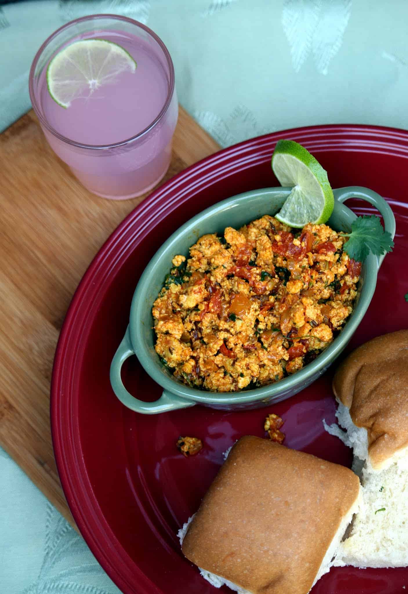 scrambled paneer curry in a bowl with bun on the side.