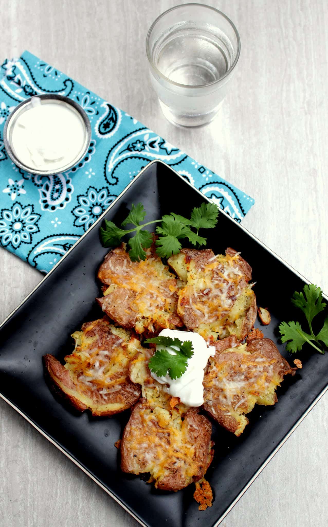 Smashed Potatoes in a black plate with sour cream as garnish