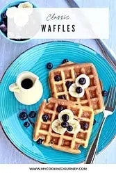 Waffles topped with banana and blueberry with syrup.