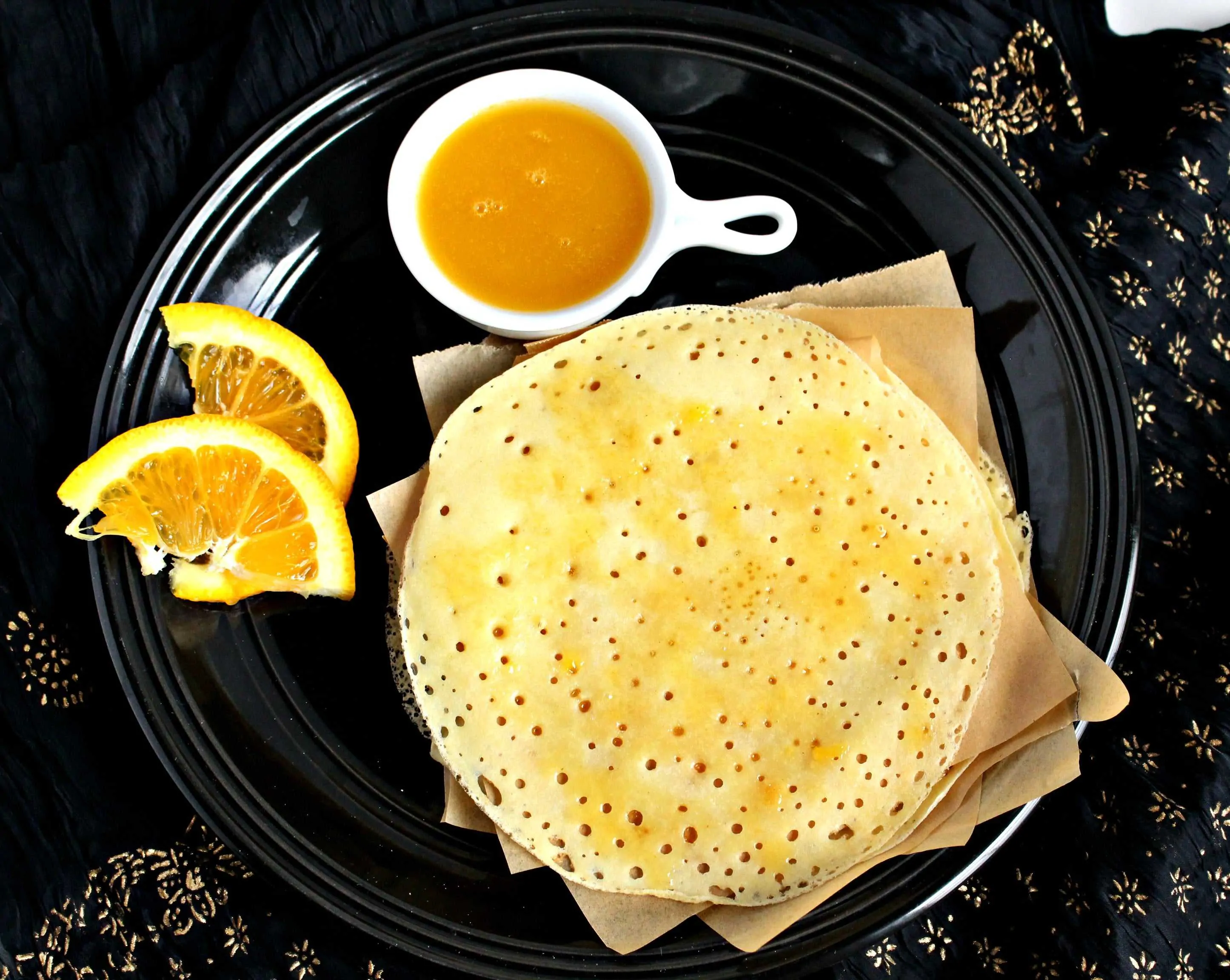 Moroccan Semolina Pancake in a black plate with sauce on the side