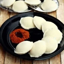 Idli in a balck plate with podi