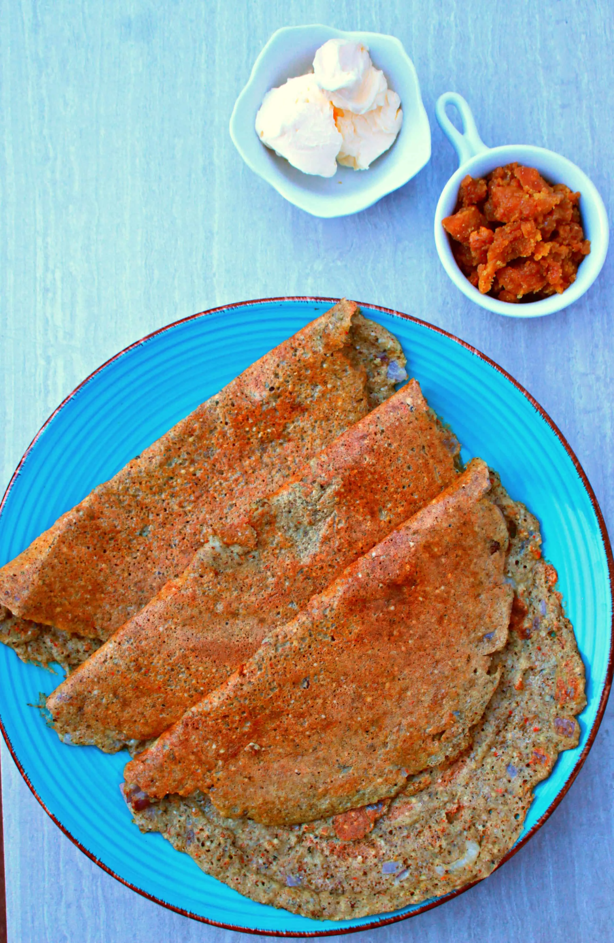 adai dosai on a blue plate with jaggery on the side