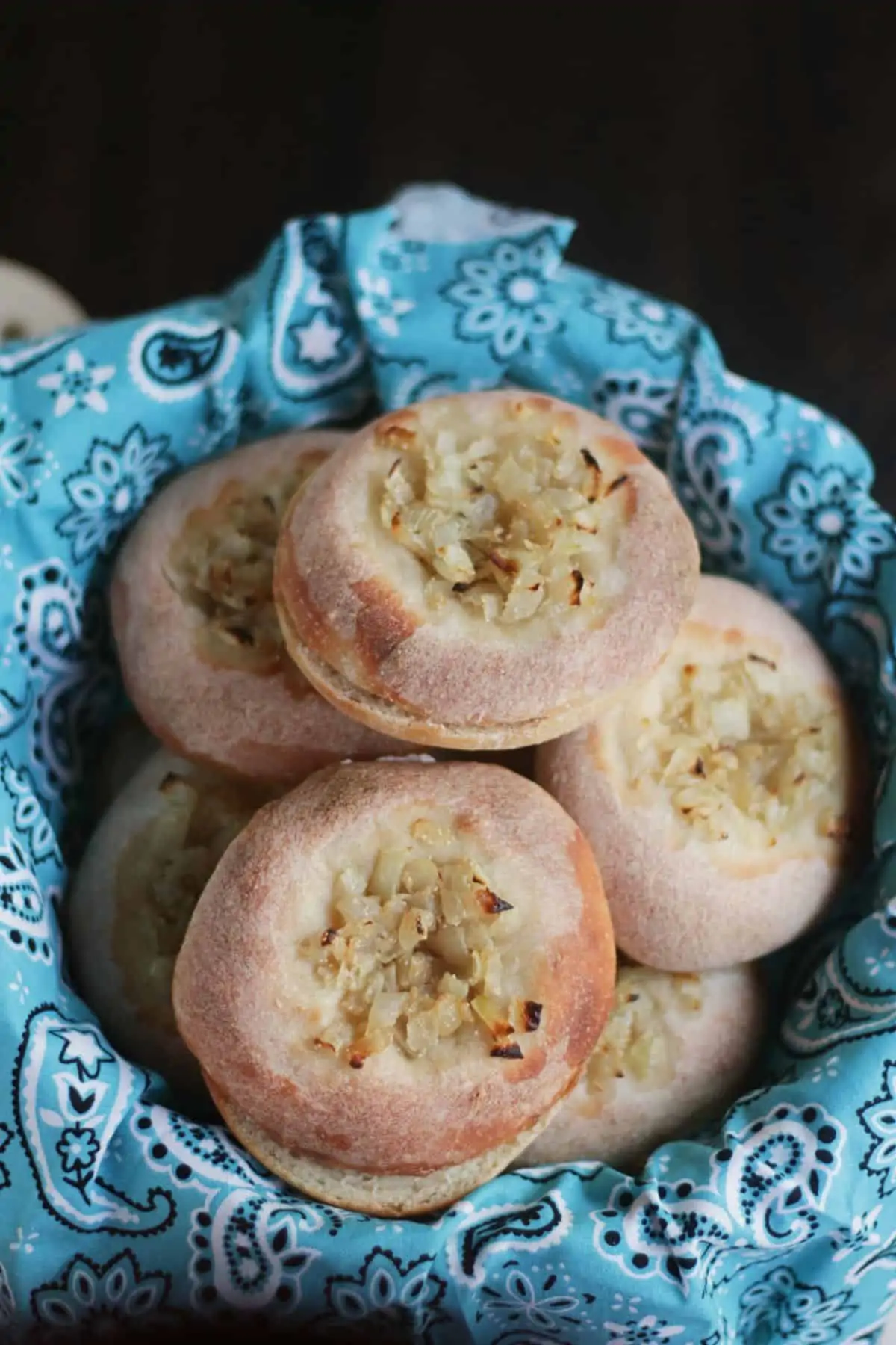 Bialys with onion topping stacked in a basket.