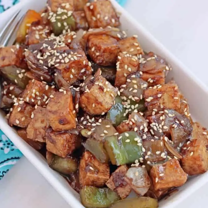 spicy fried tofu in a plate with sesame seeds on top