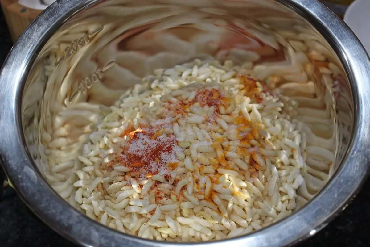 adding spices with puffed rice in a bowl