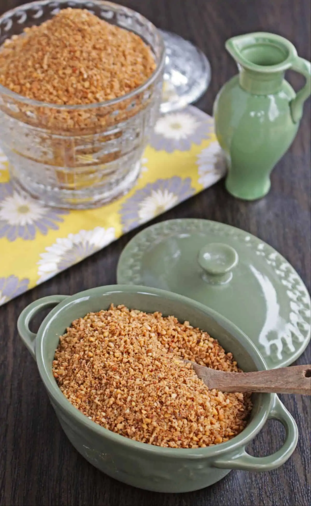 spicy coconut podi in a green container with a wooden spoon and more in the background