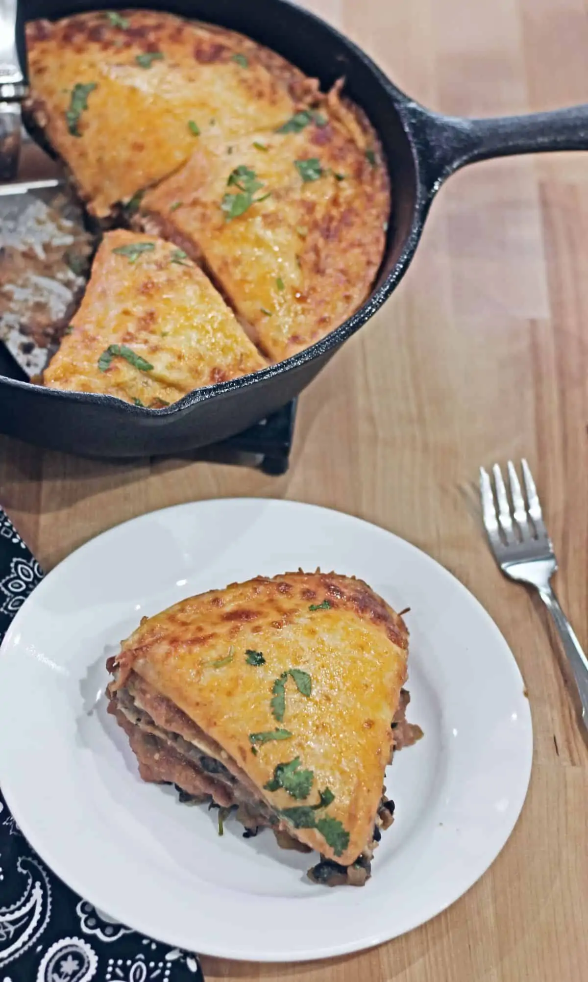 A slice of Mexican tortilla pie in a plate and remaining in a cast iron skillet in the background