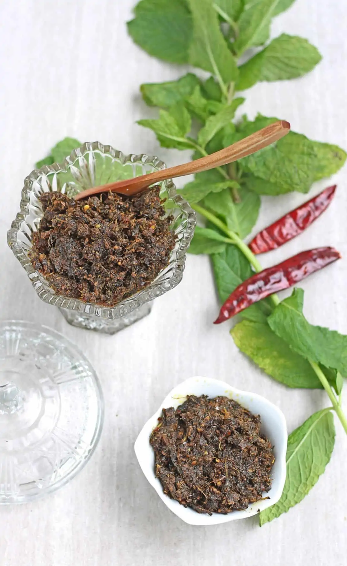 pudina thokku in glass bowl and jar along with mint leaves in background