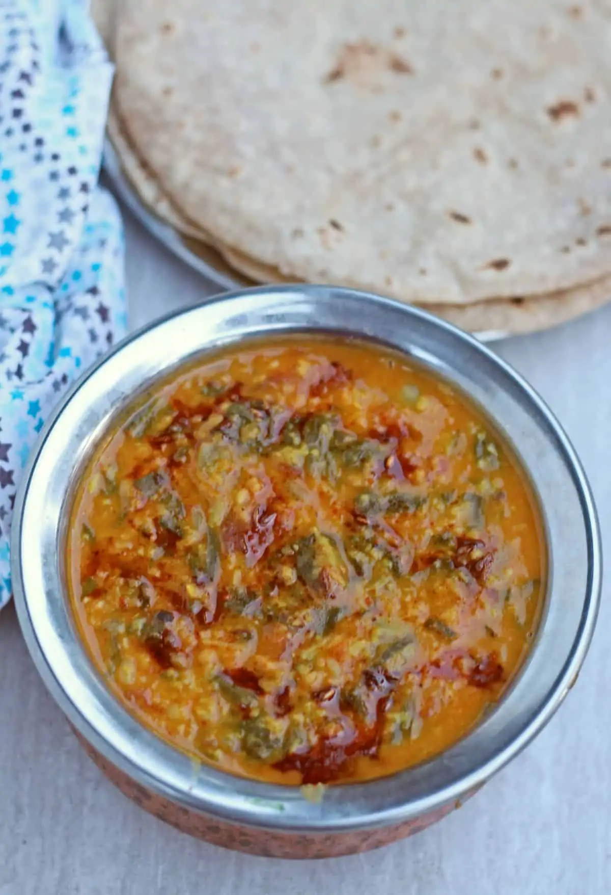 beetroot leaves and dal in a bowl with roti in the background