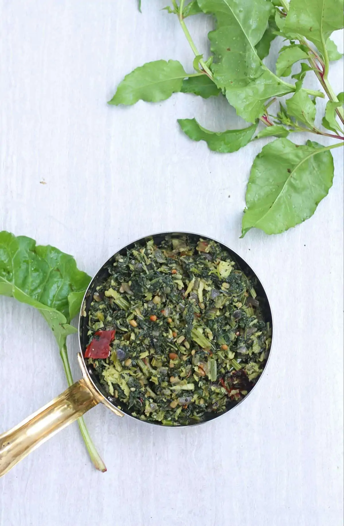 beet green poriyal in a bowl with beetroot leaves in the background