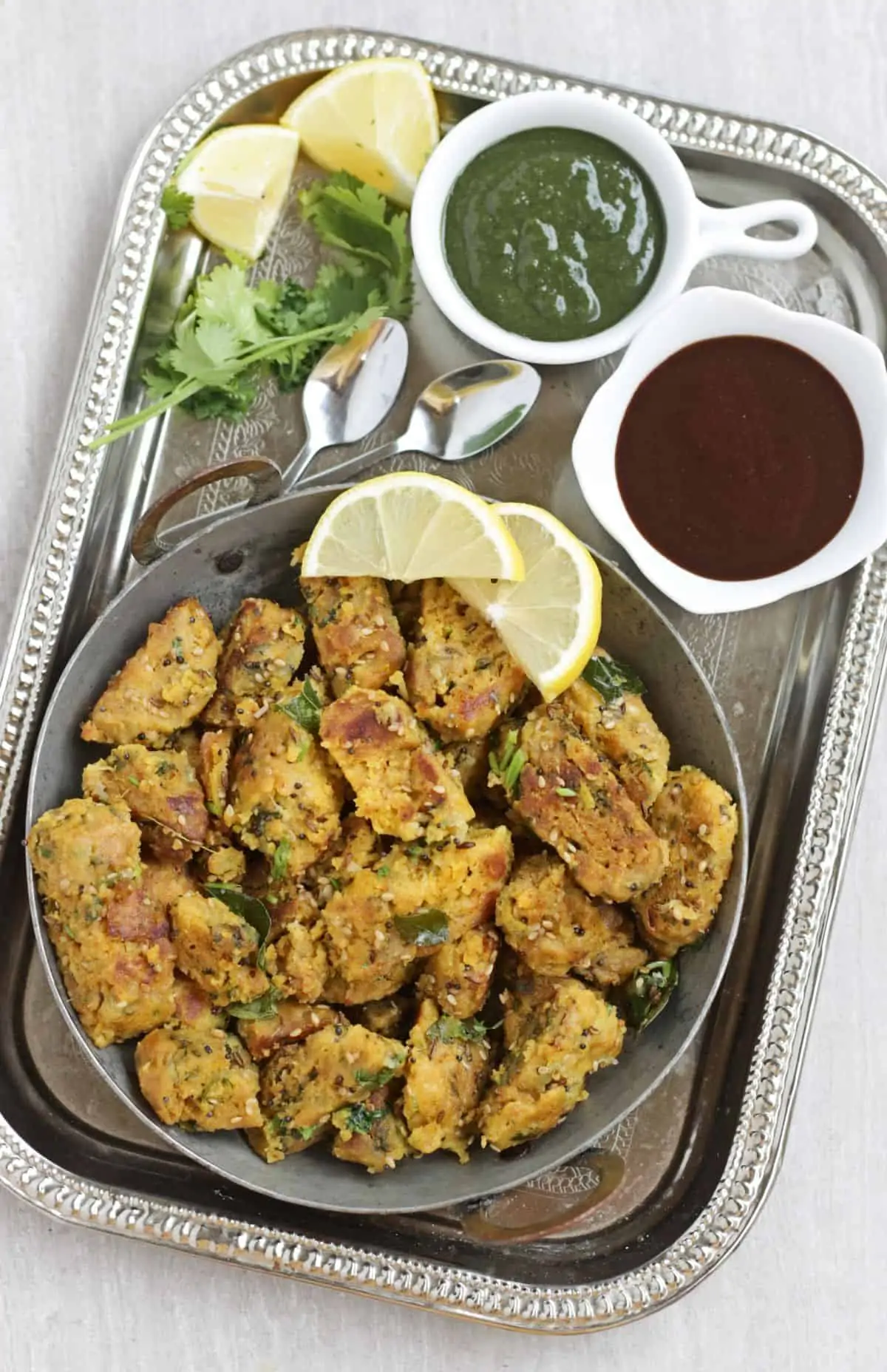 lauki muthiya in a plate with lemon slices as garnish and chutney on side