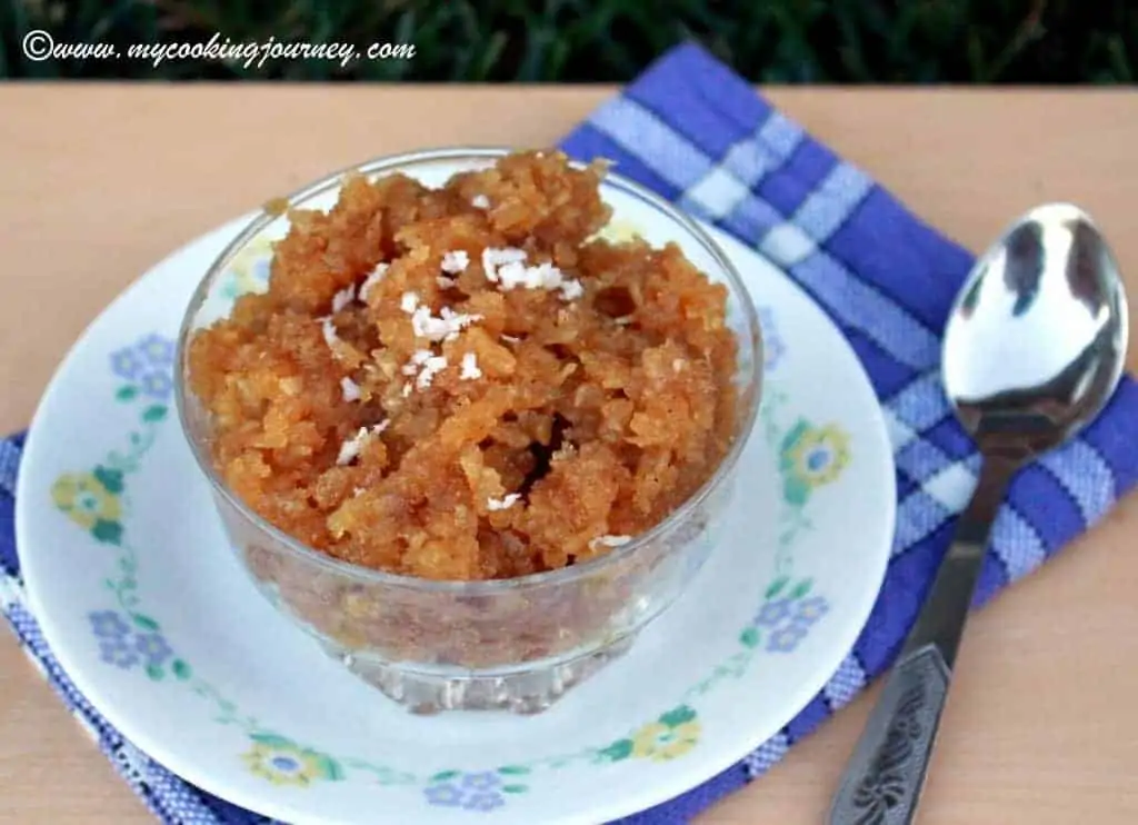 Vellam Aval in a glass bowl with roasted coconut on top.