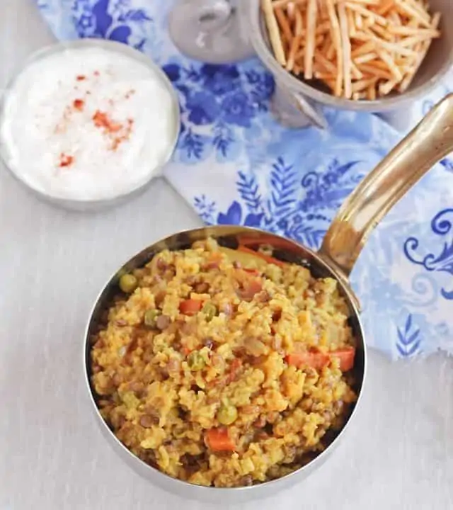 Vegetable masala khichdi with yogurt and chips in the background