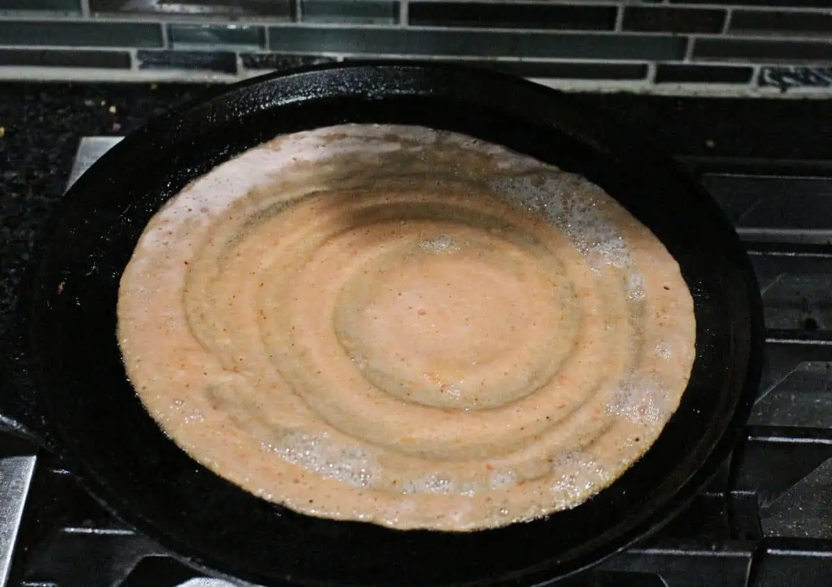 shaping the tomato dosai on cast iron pan