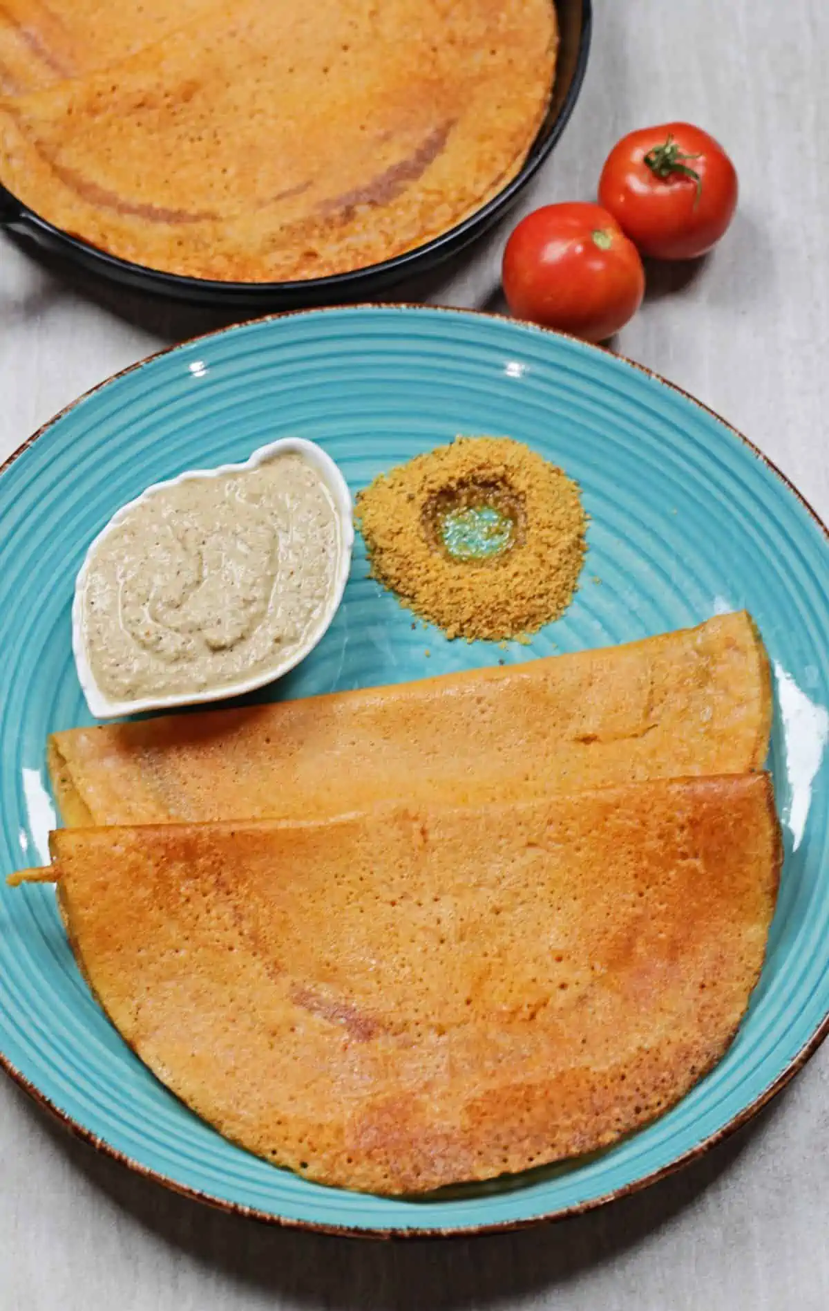 dosai chutney and idli podi on a blue plate