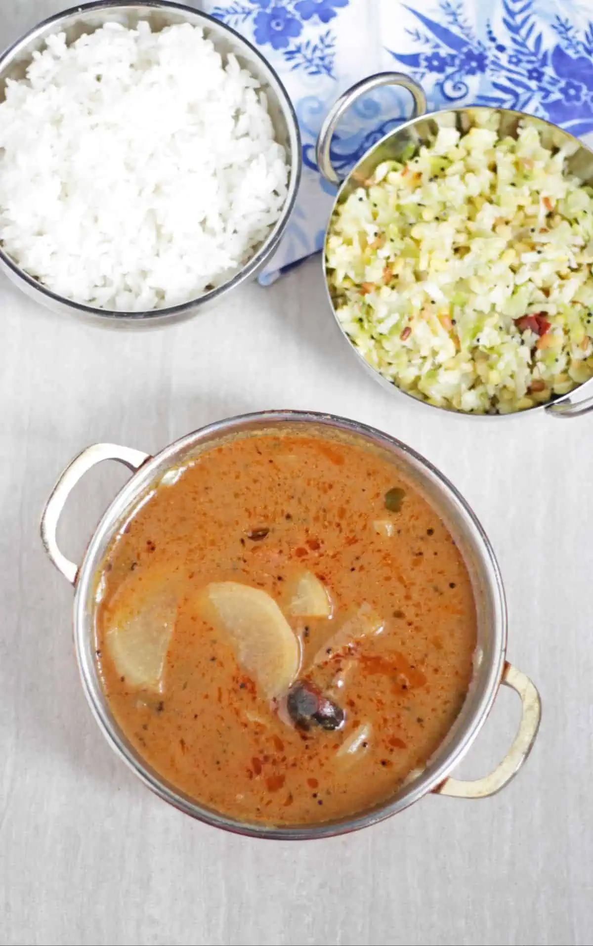 Mullangi vathal kuzhambu wih rice and curry in the background.