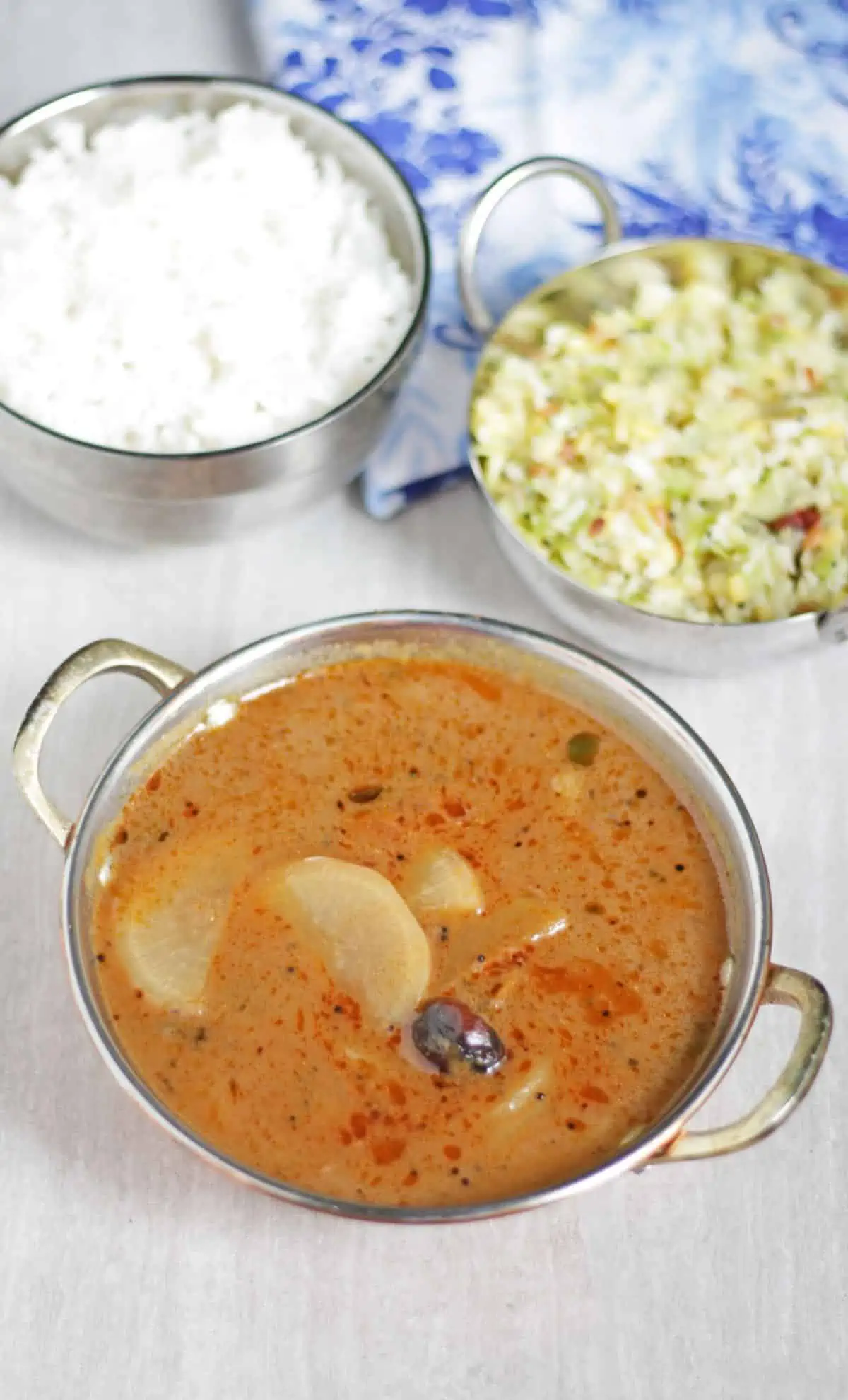 Radish kuzhambu with rice and poriyal in the background. 