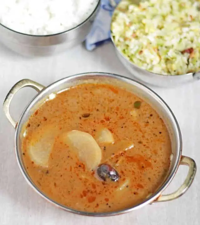 Radish kuzhambu with rice and poriyal in the background.