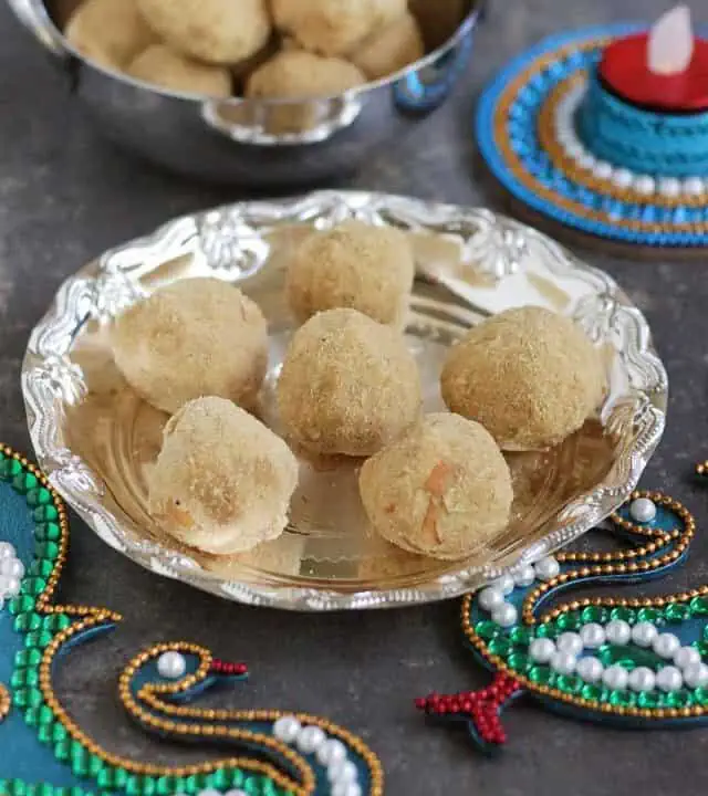 moong dal ladoo in a silver plate and more in the background with traditional decorations.