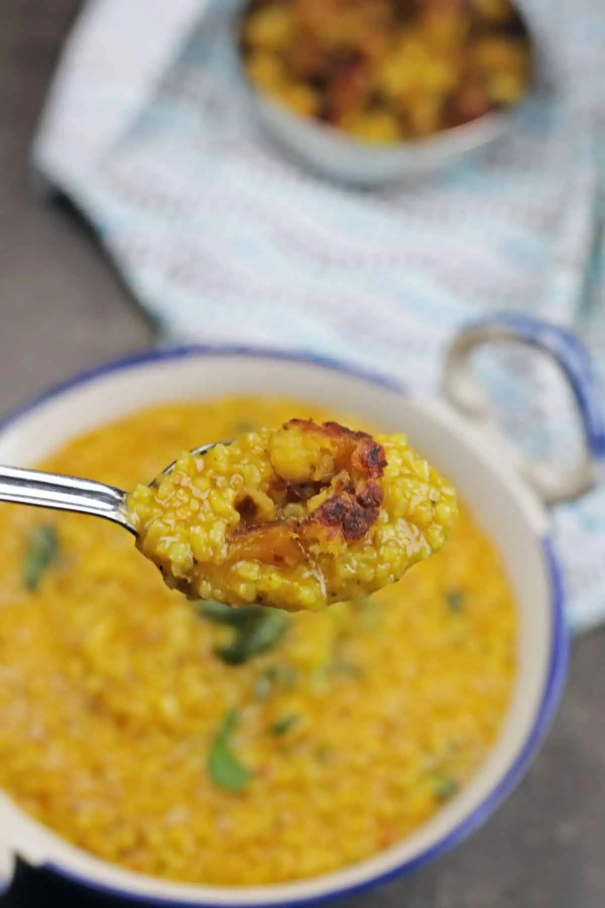 rasam sadam and potato curry scooped in a spoon.