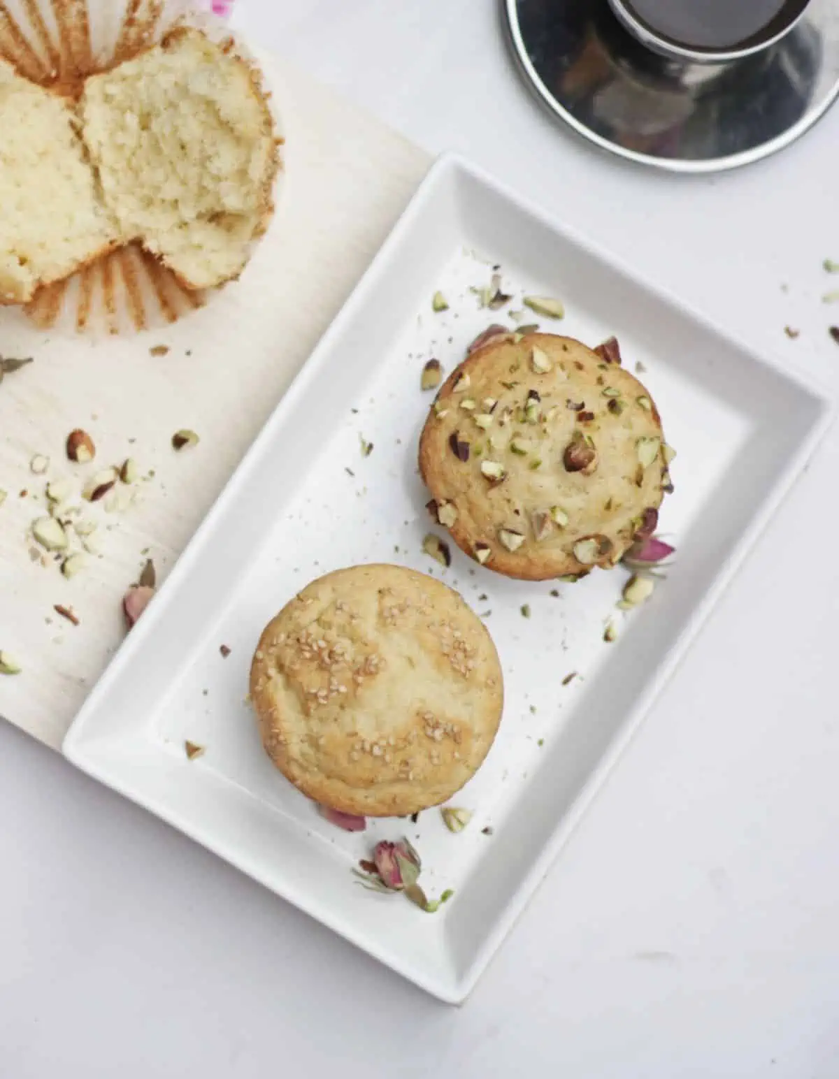 Two muffins in a white plate with garnishes.