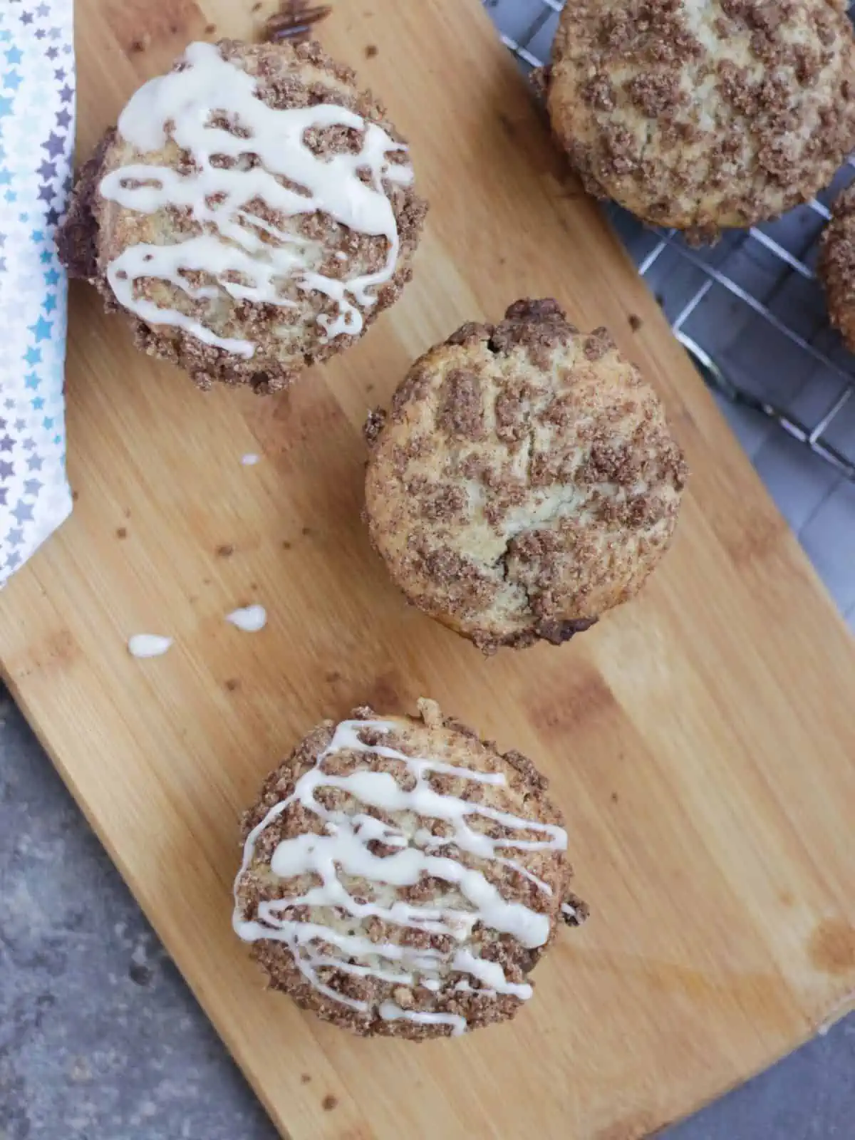 3 muffins on a wooden board drizzled with glaze.