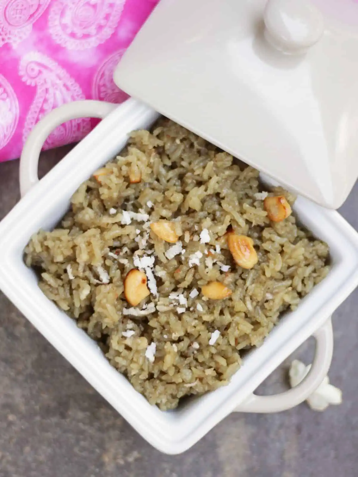 sweet jaggery rice in a white bowl garnished with cashew nuts and coconut. 