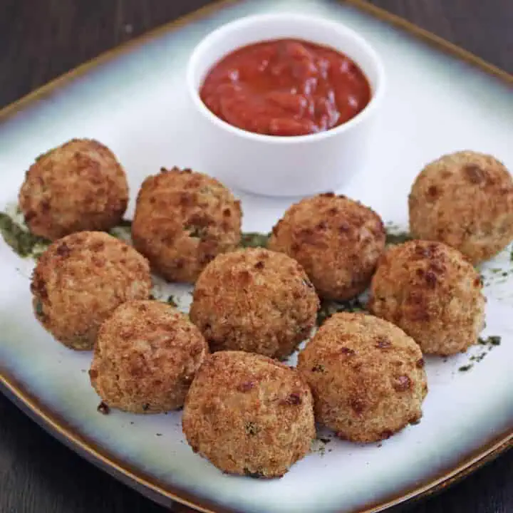 Arancini in a white plate with sauce on the side - Feature Image